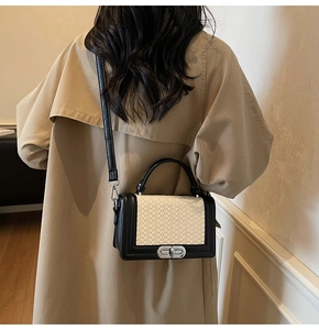 Détail d'un sac carré tissé noir et blanc porté sur un trench-coat élégant et moderne