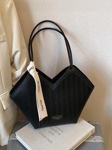Minimalist black tote bag with chevron pattern and decorative ribbon in a chic setting