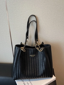 Black woven tote bag with gold chain strap and front logo patch for daily commute