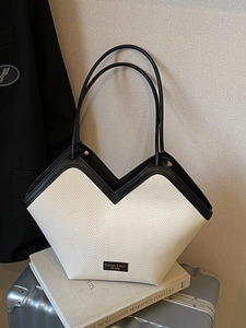 Minimalist large tote bag with cream woven texture and black leather straps on luggage