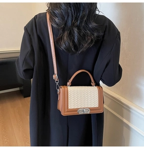 Détail du petit sac tissé contrasté avec bordure en cuir marron et fermoir métallique