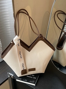 Chic tote bag with herringbone weave and brown faux leather trim on a dark surface