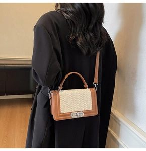 Détail du sac bandoulière tissé avec garniture en cuir brun et fermoir porté par un modèle