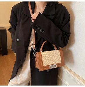 Détail du sac en cuir marron avec panneau tissé beige et fermoir rotatif argenté porté par le mannequin