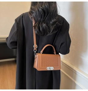 Vue arrière d'un mannequin portant le sac bandoulière tressé marron avec un manteau noir