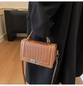 Vue détaillée de la texture tressée marron du sac avec fermoir rotatif en argent