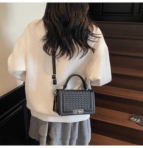 Détails du tissage noir sur le sac à bandoulière en cuir avec fermoir rotatif argenté