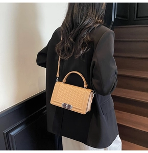 Détail du sac bandoulière tissé camel avec fermoir en métal porté par un mannequin