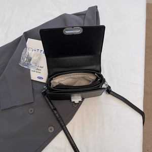 Sac bandoulière minimaliste en cuir noir avec fermoir argenté et compartiments internes