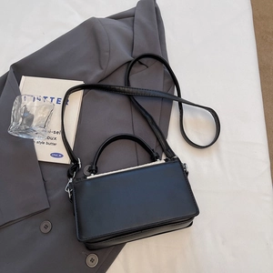Sac bandoulière carré noir tissé pour femme avec chaîne et poignée sur un blazer