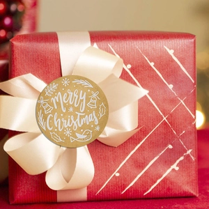 Close-up of Merry Christmas kraft sticker label on red gift box with warm bokeh lights