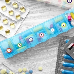 7-day blue translucent pill organizer with number stickers on white wood background