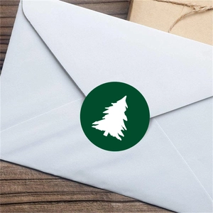 Green Christmas tree adhesive sticker labels on white envelopes for festive packaging