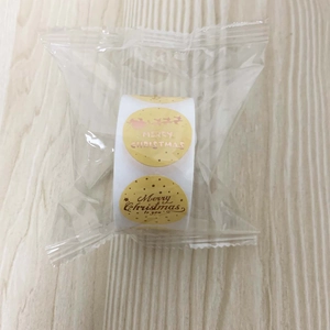 Detail of gold foil Merry Christmas sticker roll with Santa and reindeer in plastic wrap
