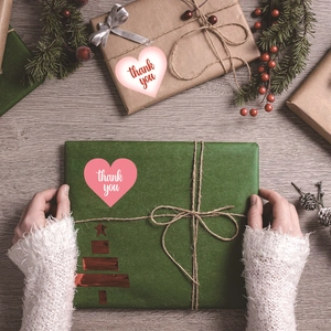 Adesivi Thank You a forma di cuore su una confezione regalo festiva su legno