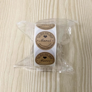 Macro shot of kraft paper stickers on a roll with Merci and heart pattern engraving