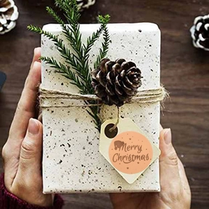 Roll of Merry Christmas gold foil stickers on a gift box with festive pine decorations