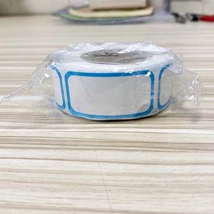 Macro shot of roll-packed white food labels with blue border on a wooden table