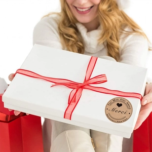 Brown kraft paper stickers featuring Merci and heart design on a white gift box with red ribbon