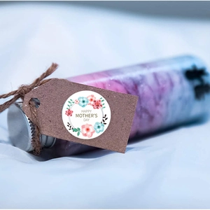 Detail of floral Mother's Day sticker on kraft tag tied to a glass gift bottle