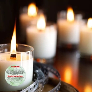 Detailed view of burning scented candles in glass jars with circular safety warning labels
