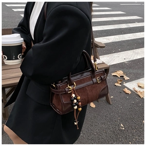 Detail of dark brown suede baguette bag with beaded tassels and gold hardware