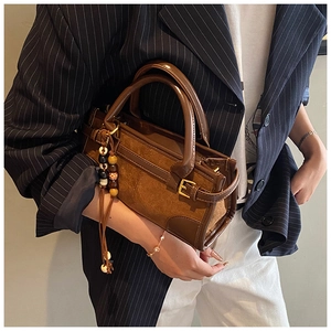 Brown leather and suede baguette bag with decorative beaded tassel held by a model