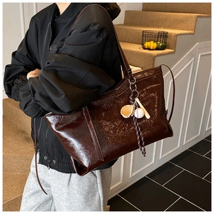 Close-up of vintage glossy leather tote bag featuring a baseball charm accessory