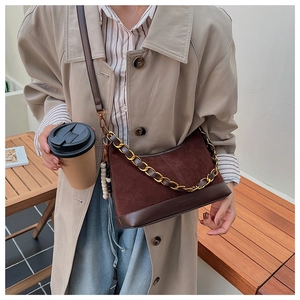 Braune Patchwork-Beuteltasche mit Metallkette, präsentiert an einem Trenchcoat-Model