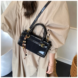 Detail of black patchwork shoulder bag with gold hardware and beaded tassel charm