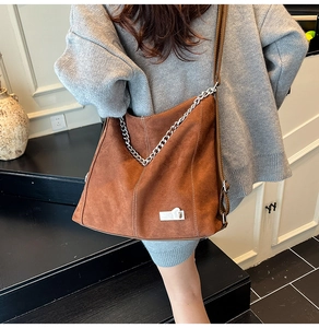 Detail der braunen Shopper-Tasche aus Wildleder mit Silberkette und Kontrastnähten
