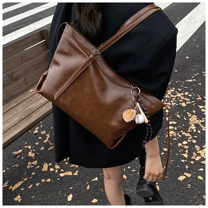 Detail of vintage dark brown tote bag with glossy leather texture and sports charm