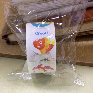 Close-up of a roll of colorful cartoon dinosaur reward stickers in plastic packaging