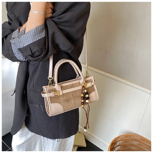 Detail of retro color-block baguette bag with suede texture and wooden bead tassel