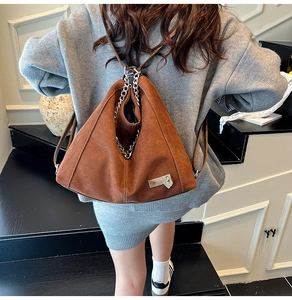 Detail der braunen Vintage-Tasche mit Silberkette und Herzanhänger auf der Treppe