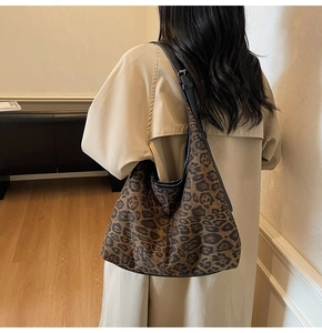 Detail view of large leopard print tote bag with black strap worn by a model