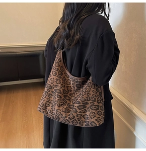 Detail of large leopard print suede tote bag with brown leather trim on female model