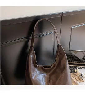 Detail of dark brown faux leather tote bag showing vintage texture and durable long handles
