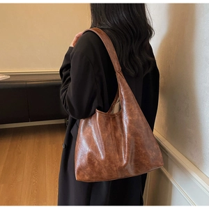 Dettaglio della borsa hobo in pelle marrone caramello con texture vintage e tracolla larga