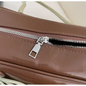 Macro detail of smooth silver metal zipper and dark brown glossy PU leather bag