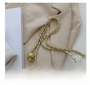 Detail of white quilted bag featuring a gold chain strap with a spherical metal adjuster