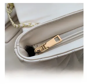 Detailed macro view of the smooth gold zipper and quilted leather texture on the beige bag