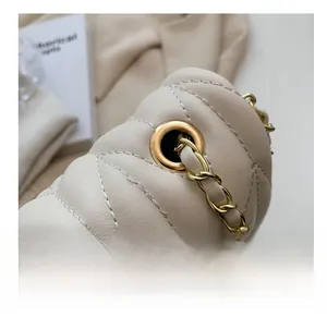 Detailed close-up of beige quilted leather stitching and premium gold metal chain hardware