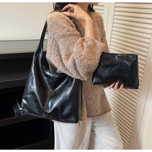 Detail of black large capacity tote and clutch set with glossy wrinkled leather texture