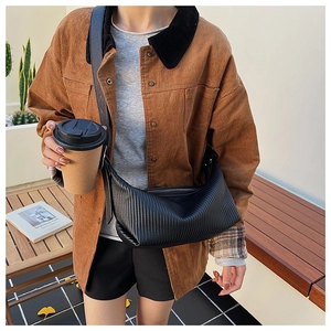 Detail of black pleated crescent crossbody bag paired with a brown corduroy jacket