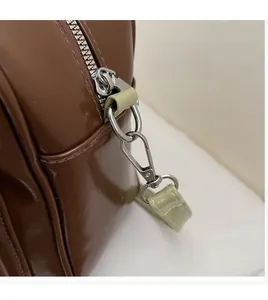 Detail of durable silver hook and zipper on dark brown glossy faux leather shoulder bag