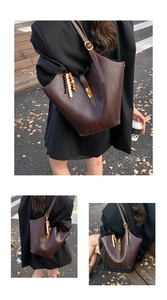 Detail of deep brown woven texture tote bag with gold buckle and beaded charm