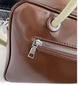 Detail of smooth silver zipper and high-quality leather stitching on a brown tote bag