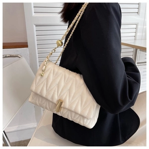 Close-up of cream quilted chain bag featuring V-shaped stitching and gold ball adjuster