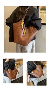 Detail of brown woven tote bag featuring a V-shaped texture and wooden bead charm